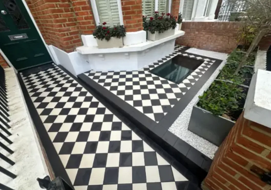 Victorian style black and white geometric mosaic tiled front path with a black border